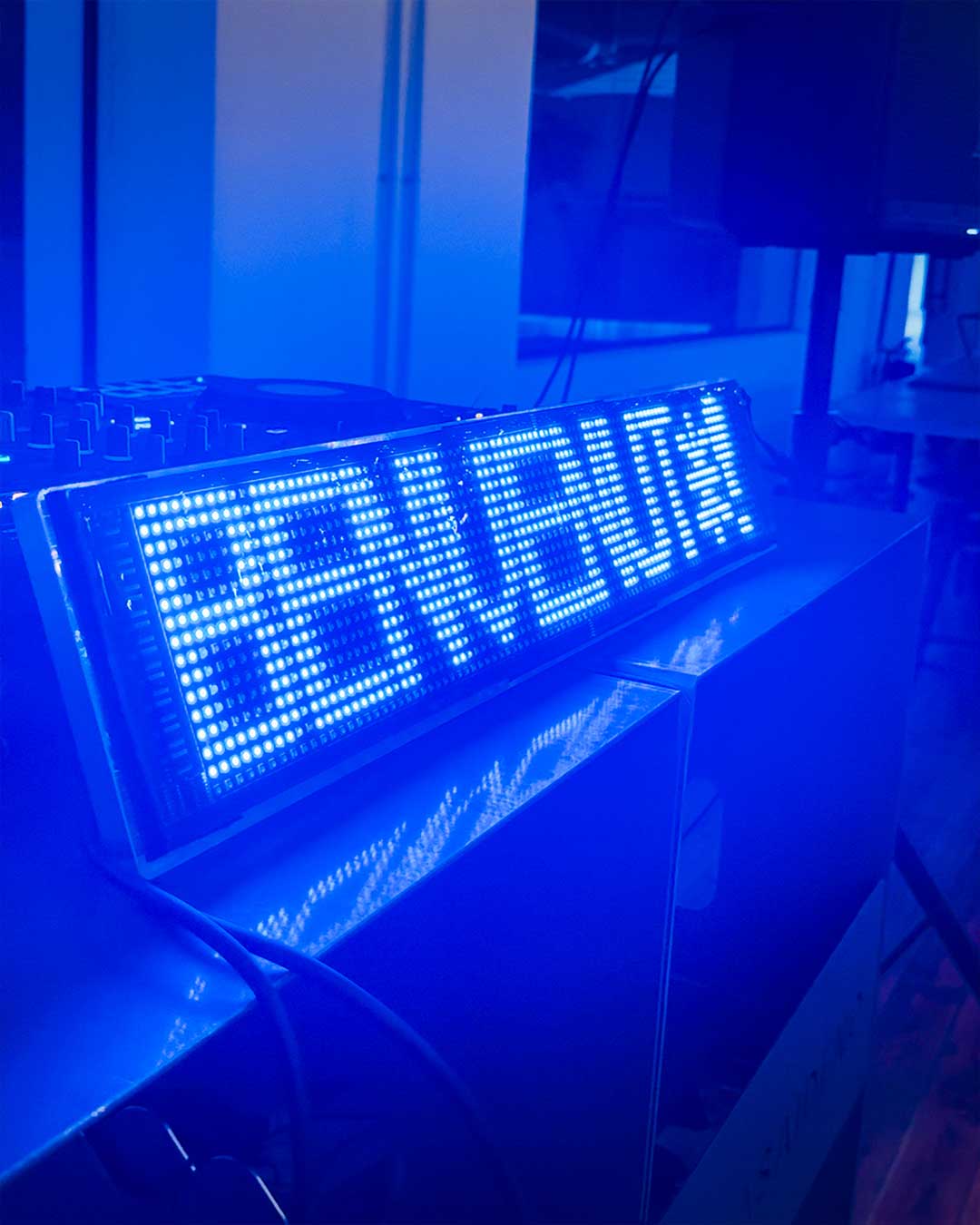 Scritta luminosa Area Saideno con luce blu, dettaglio set evento privato.